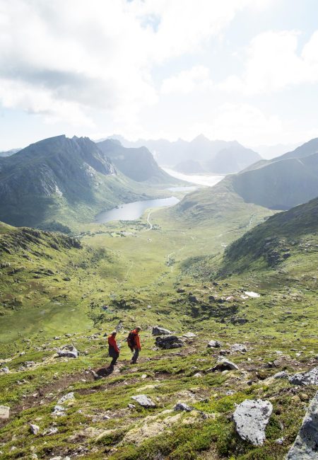 A vertical shot of people hiking in the mountains of Lofoten Islands on a cloudy weather